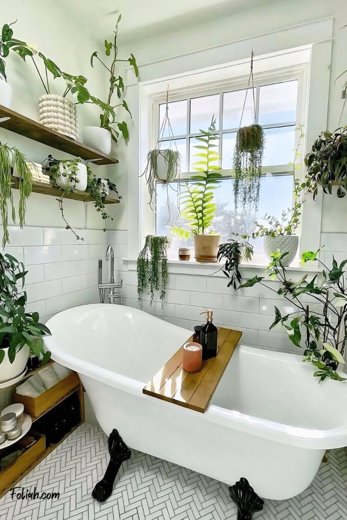 These Tiny Bathrooms Are Proof You Don’t Need a Lot of Room to Decorate with Plants 4 at Foliah Bright bathroom with a white clawfoot tub, herringbone tile floor, and a large window surrounded by lush houseplants including hanging string of pearls, a zigzag cactus, philodendron, spider plant, and ferns on shelves, windowsill, and floor.