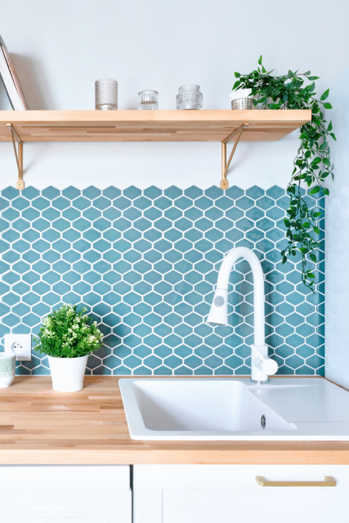 13 Gorgeous Kitchen Plant Styling Ideas You’ll Want to Copy 12 at Foliah Modern kitchen with teal backsplash, white sink, wooden countertop, and green plants like pothos, basil, and fern for a fresh, inviting look.
