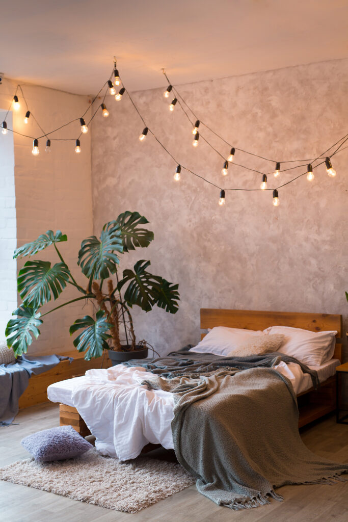 Bedroom with a large monstera plant placed beside the bed, creating a simple and relaxed plant styling idea.