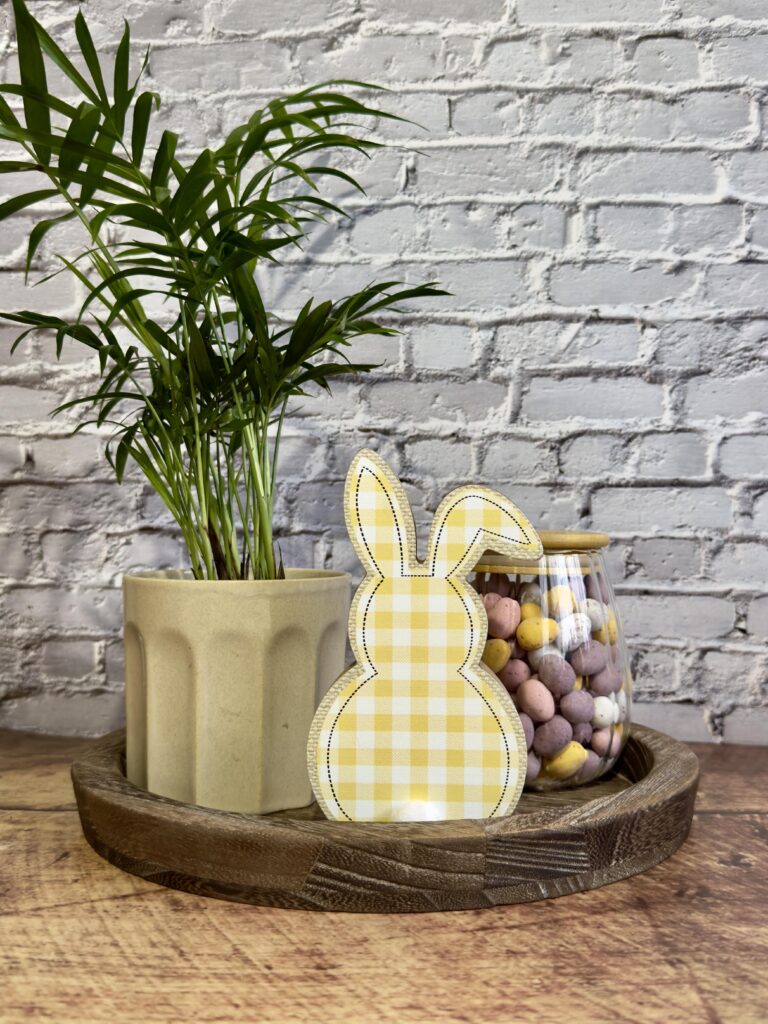 Small tray styled with a potted plant, Easter bunny decor, and jar of eggs for simple Easter plant decor.
