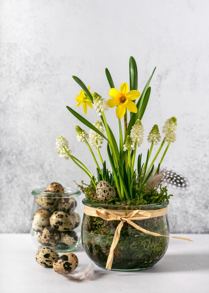 Glass jar filled with moss, spring bulbs, and quail eggs for a simple and fresh Easter plant display.