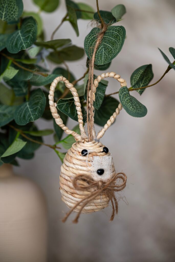 Handmade bunny ornament hanging from a leafy indoor plant for a simple and natural Easter decoration.