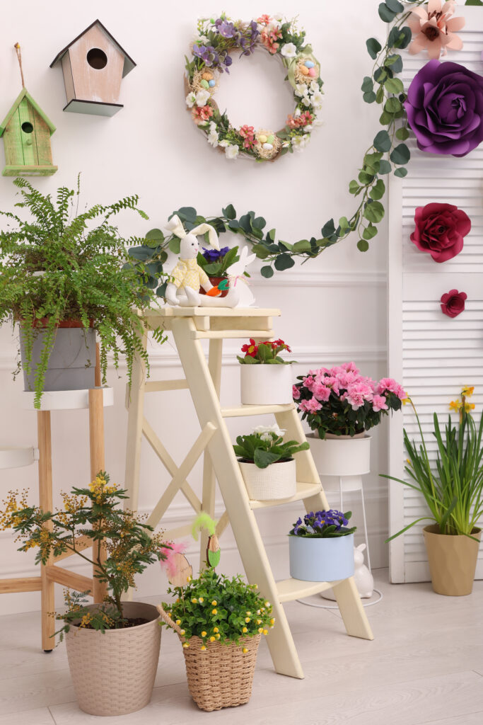Indoor plant corner styled with flowers, wreath, and Easter decorations including bunnies and colorful accents.