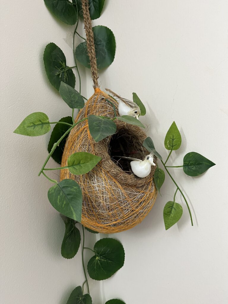 Hanging nest decoration styled with trailing greenery for natural Easter plant decor on a wall.