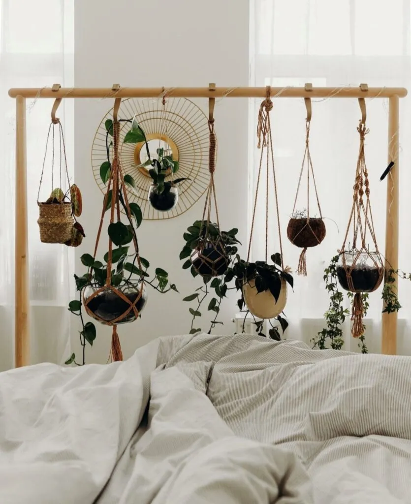 Bedroom with multiple hanging plants at different heights above the bed, creating a layered indoor plant display.