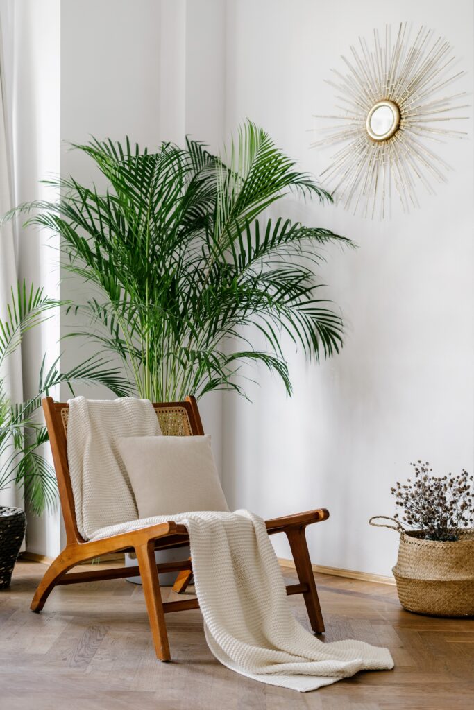 Vertical shot of bright living room in boho chic style with white knitted plaid on comfort rattan armchair. Wicker chair, potted house plants, home decor in modern apartment